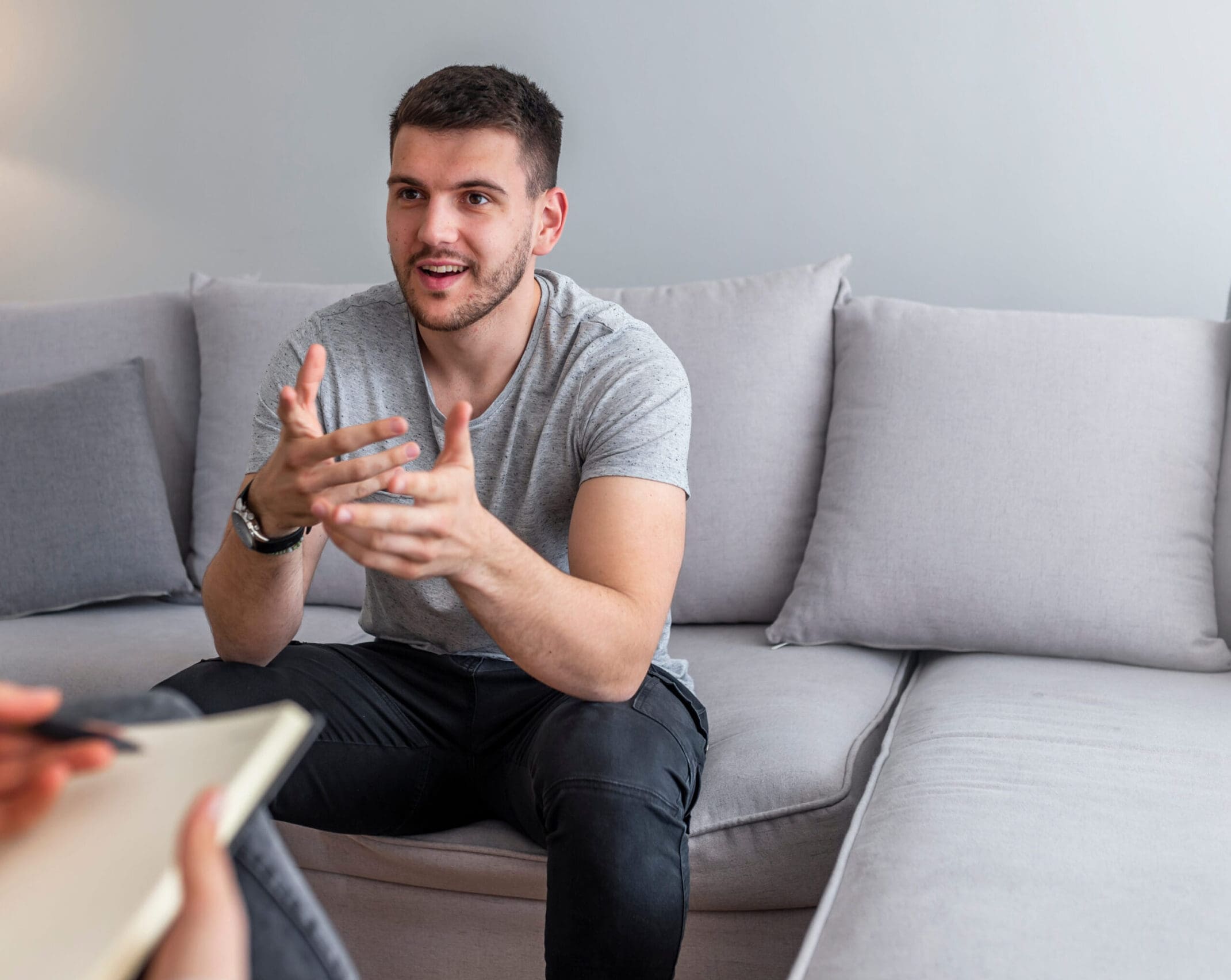 Psychologist talking with happy man in the office. Image of young man during psychological therapy. Female psychologist consulting man during psychological therapy session